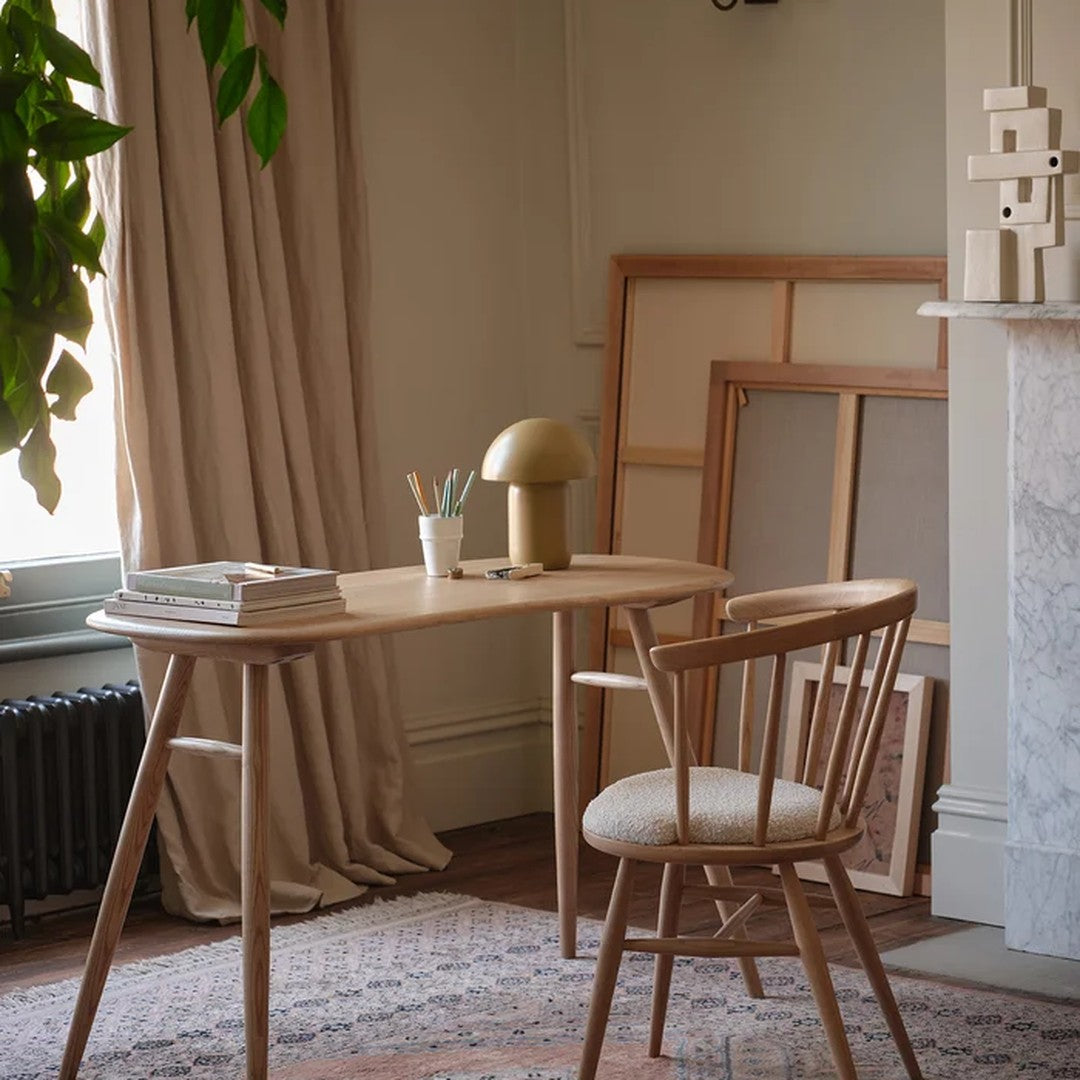 Wooden table and chair in soft beige and earthy tones, with a subtle patterned rug and greenery accent.