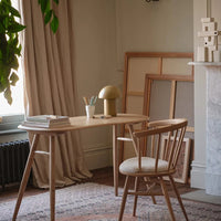 Wooden table and chair in soft beige and earthy tones, with a subtle patterned rug and greenery accent.
