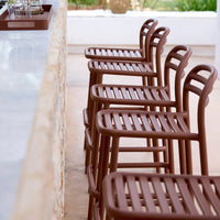 Brown slatted bar stools lined up, featuring a smooth matte finish against a light stone countertop.