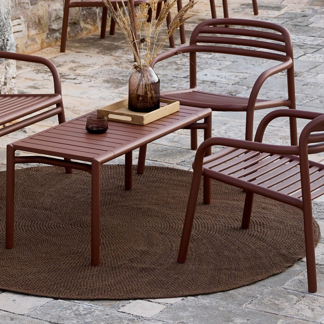 "Brown outdoor furniture set with slatted design on a textured brown circular rug, perfect for stylish patio decor."