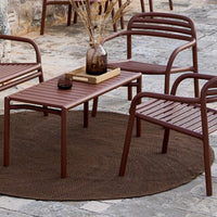 "Brown outdoor furniture set with slatted design on a textured brown circular rug, perfect for stylish patio decor."