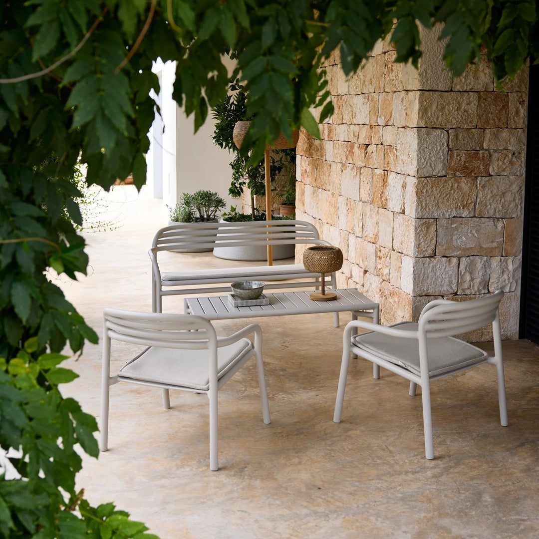 Light grey outdoor seating set with minimalist design, featuring soft cushions and a modern stone table.