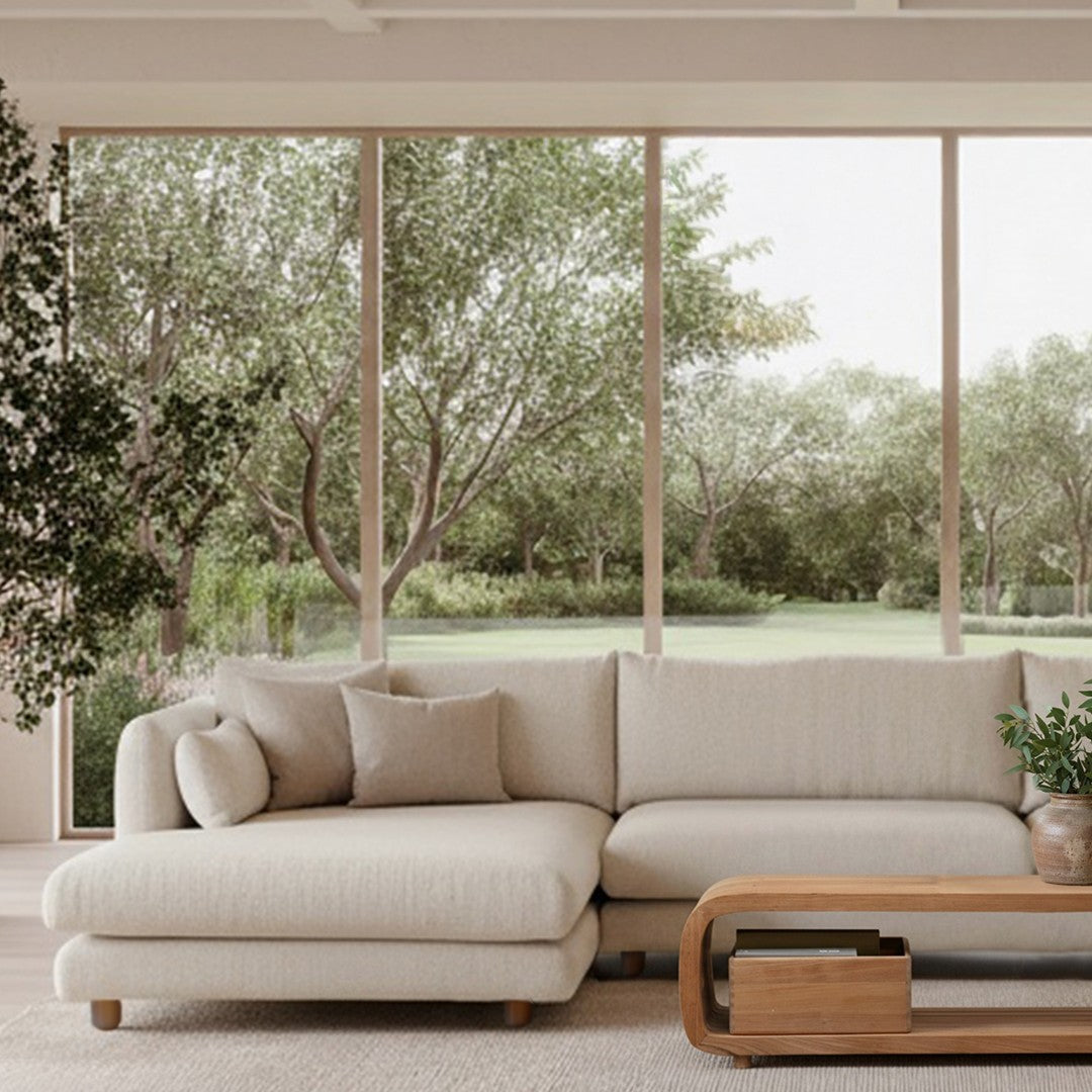 Light beige sofa with a soft fabric texture, complemented by green plants and a natural outdoor view.