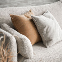 Beige textured sofa with orange and gray pillows, showcasing a cozy, neutral color palette and soft patterns.