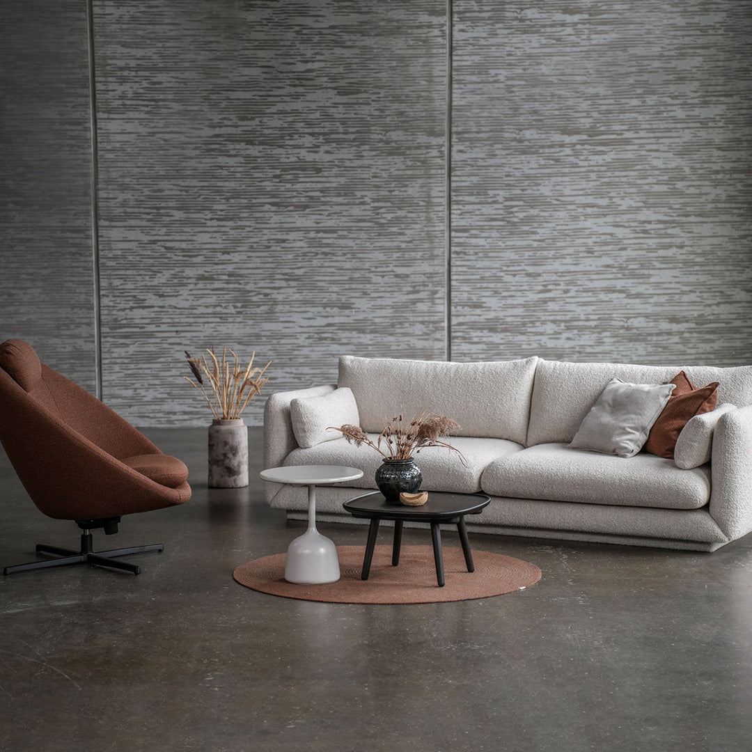 Modern living room featuring a beige sofa, brown accent chair, and gray decor. Textured patterns and earthy tones create elegance.