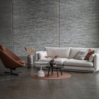 Modern living room featuring a beige sofa, brown accent chair, and gray decor. Textured patterns and earthy tones create elegance.