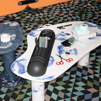 Black product on a white table featuring blue marbled patterns, surrounded by a colorful geometric carpet.