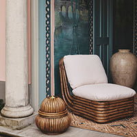 Light beige cushion on a woven rattan chair, paired with a round decorative basket in warm wood tones.