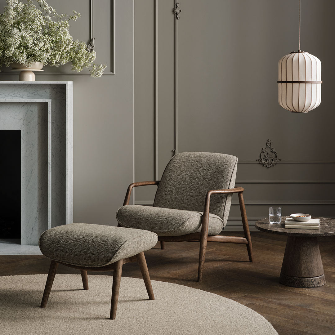 Modern grey armchair and ottoman with textured brown upholstery and natural wood accents, set against a neutral backdrop.