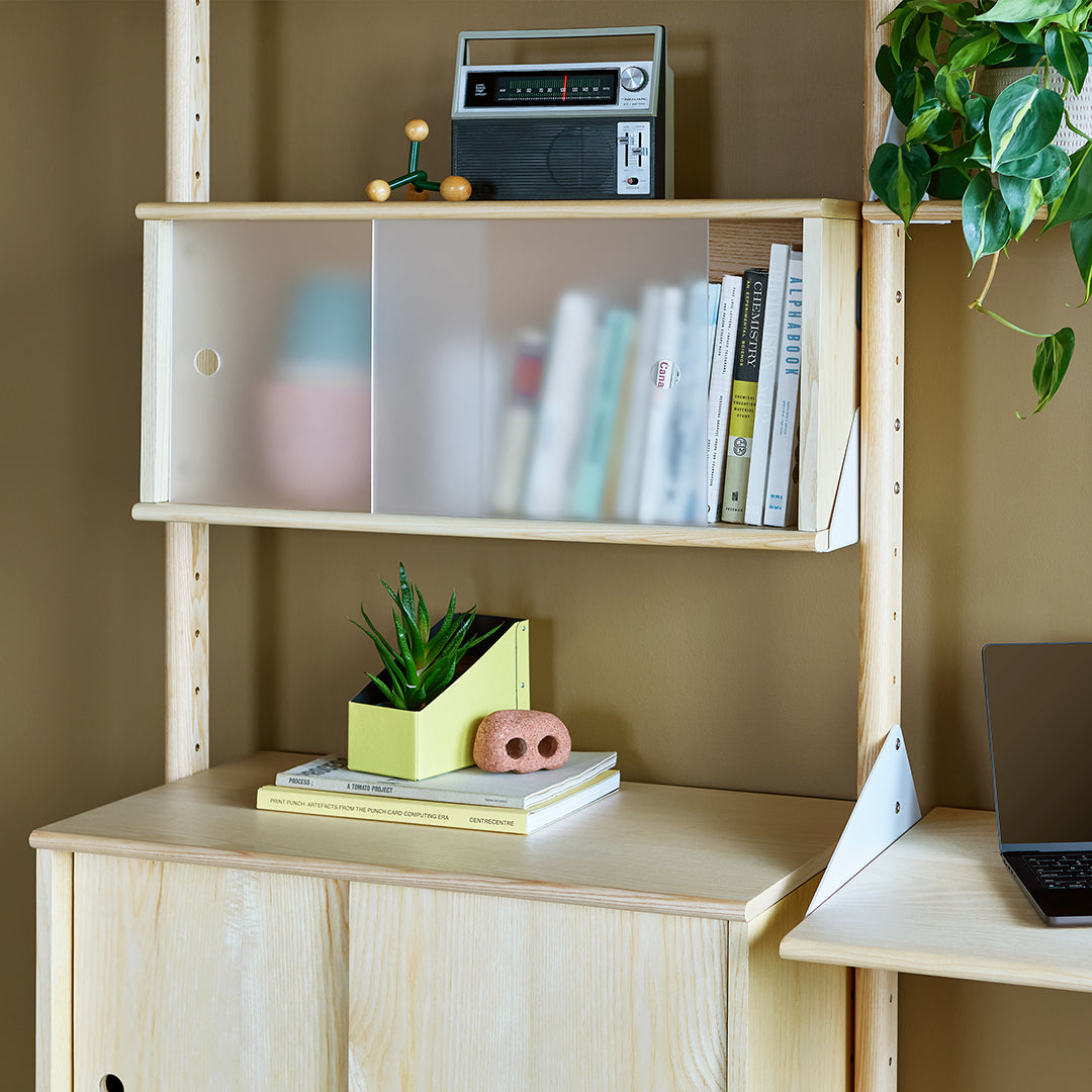 Light wood tones, green accents, soft pastel pinks, and vibrant greens create a modern, fresh look in this styled shelf.
