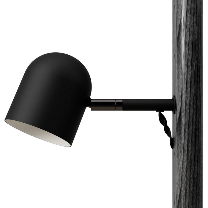Black wall-mounted lamp with a smooth, rounded shade and minimalistic design against a textured wooden backdrop.