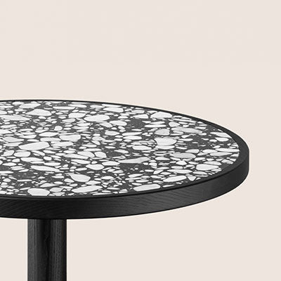 Black and white terrazzo pattern table top on a sleek black pedestal, offering a modern and stylish look.