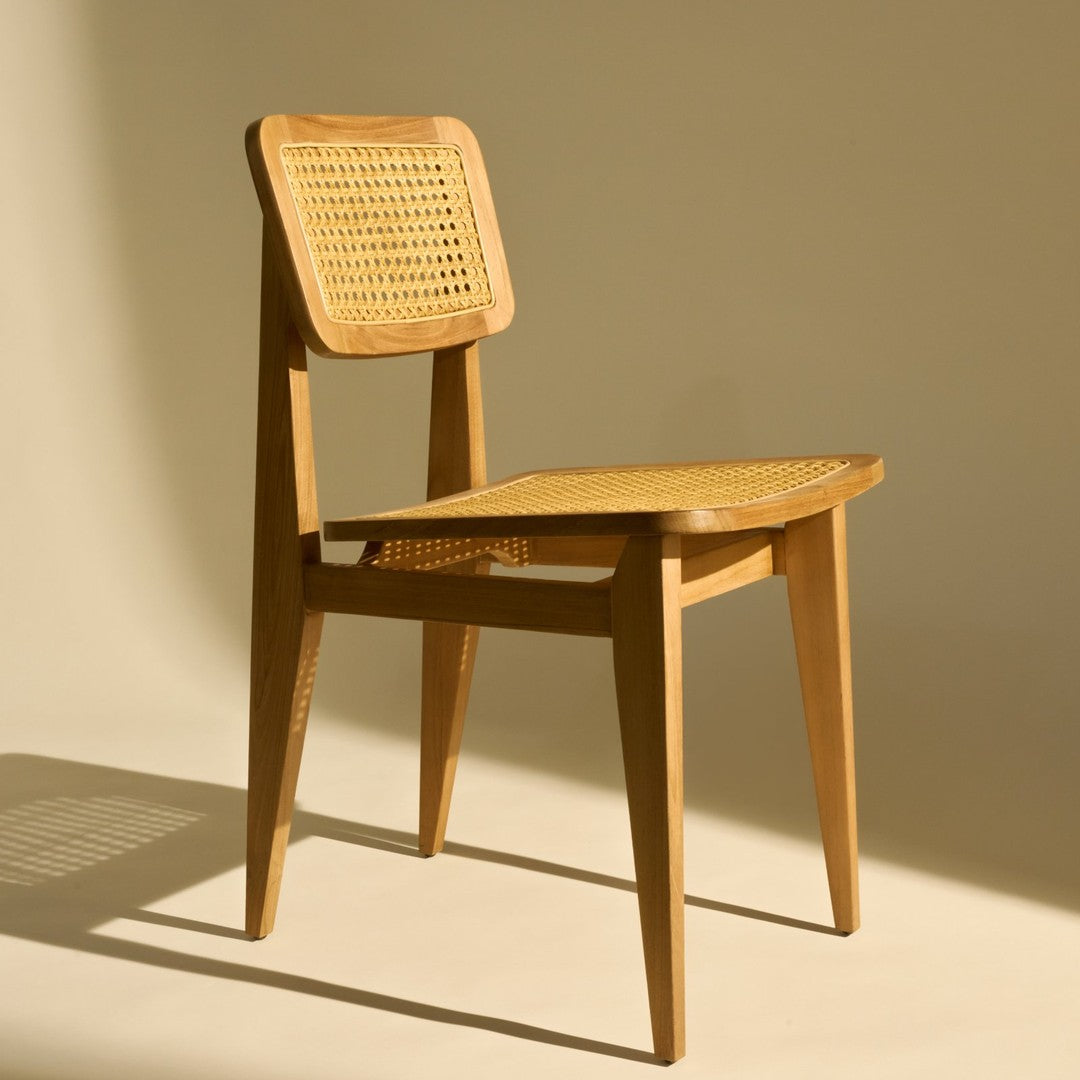 Natural wood chair with a light honey finish and woven cane seat pattern, set against a soft beige background.
