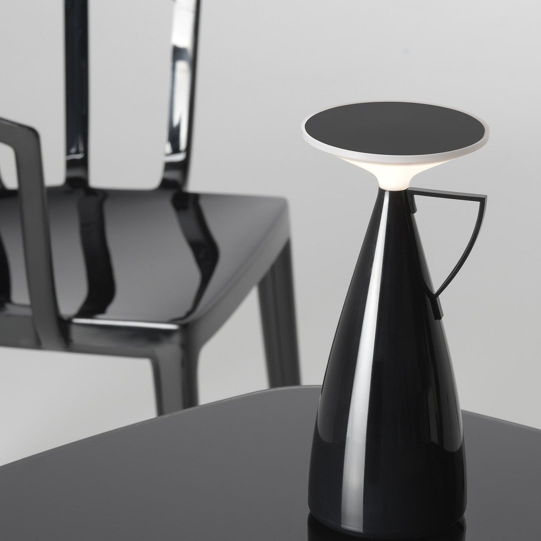 Black modern lamp with a glossy finish, featuring a sleek white top and a minimalist design against a gray backdrop.