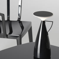 Black modern lamp with a glossy finish, featuring a sleek white top and a minimalist design against a gray backdrop.