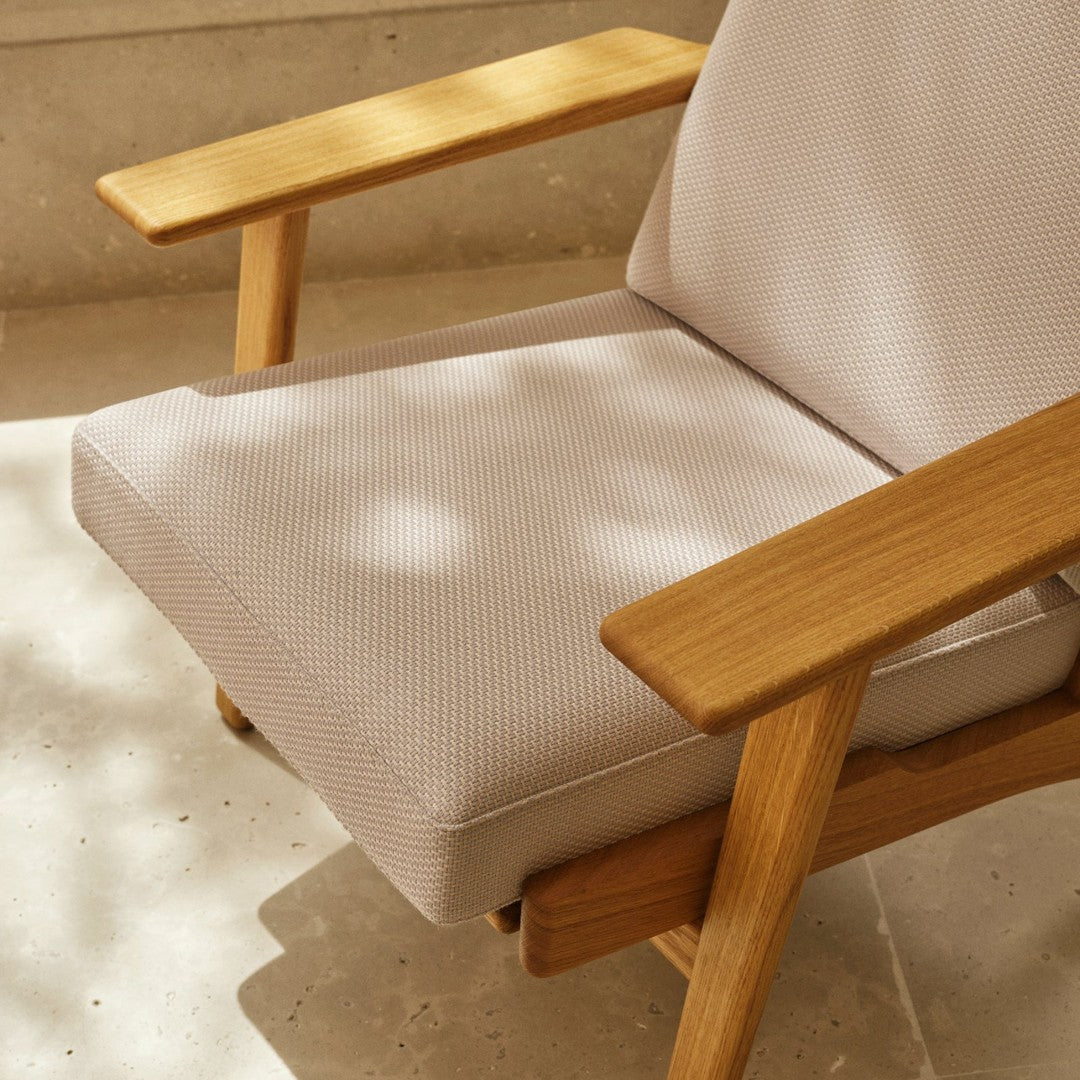 Light beige textured fabric seat cushion with natural wood armrests, showcasing a minimalist design.