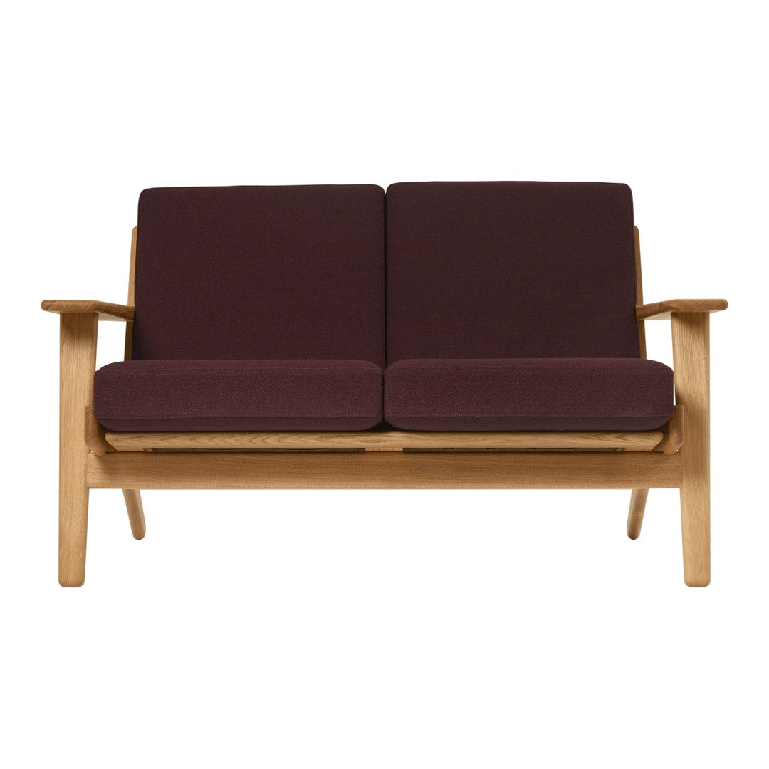 Maroon cushions on a light wooden frame sofa, featuring a simple, modern design and clean lines.