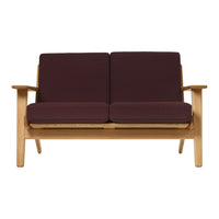 Maroon cushions on a light wooden frame sofa, featuring a simple, modern design and clean lines.