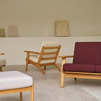 Modern furniture featuring beige, burgundy, and white cushions with natural wooden frames against a minimal background.