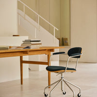 Modern ergonomic chair with a sleek black cushion and polished chrome base, set against a minimalist interior.