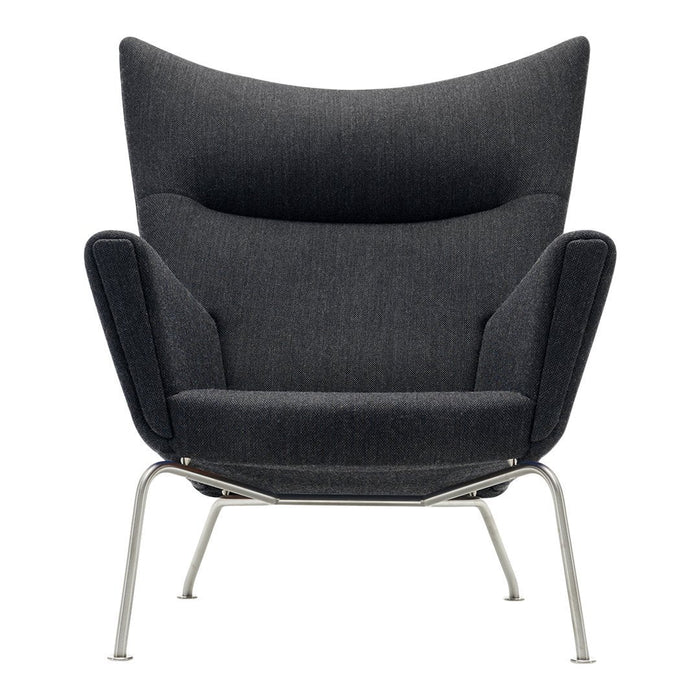 Modern dark gray armchair with a sleek, textured fabric and minimalist silver legs, featuring a stylish wingback design.
