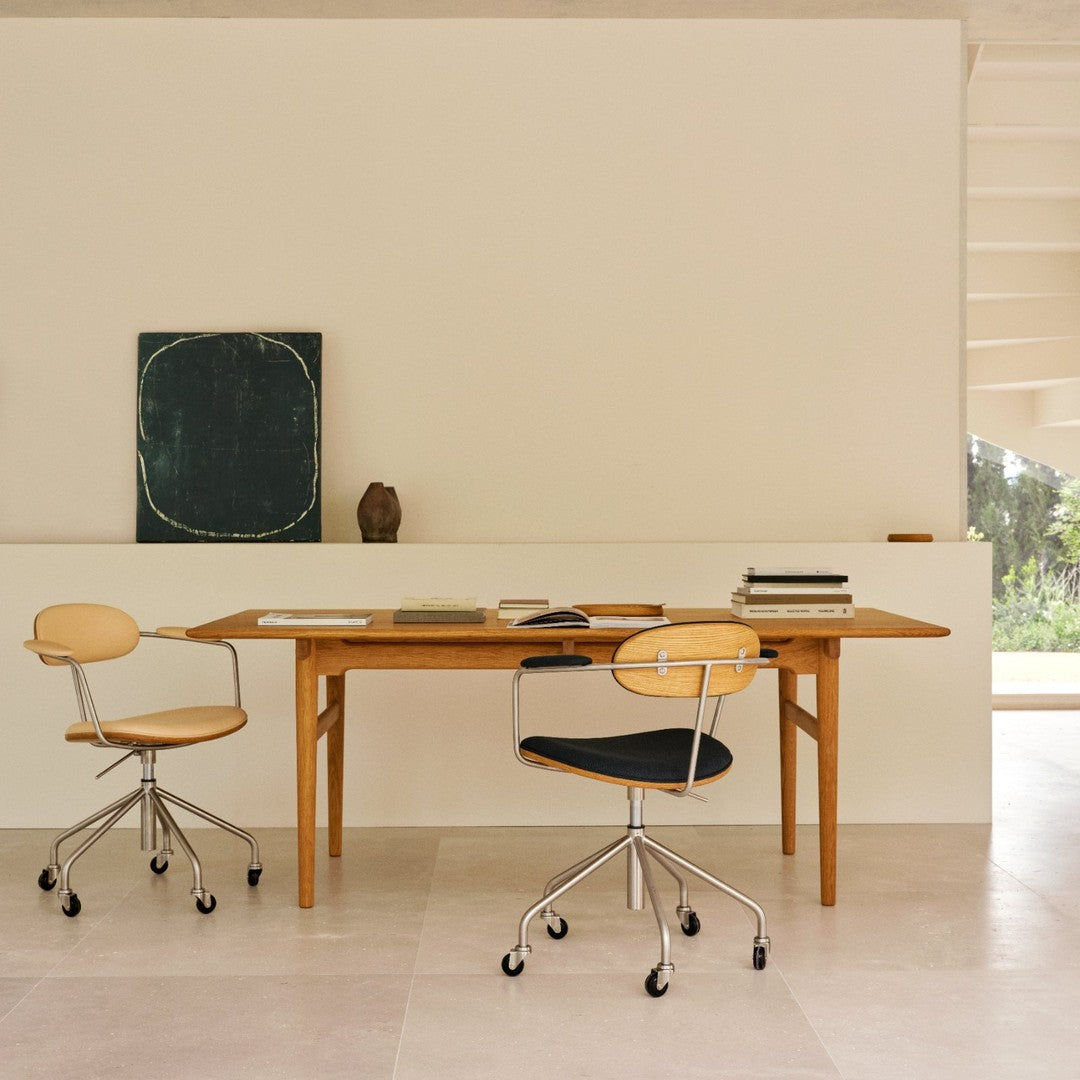 Light wood table with cream and black ergonomic chairs against a neutral wall, featuring subtle textures and muted colors.
