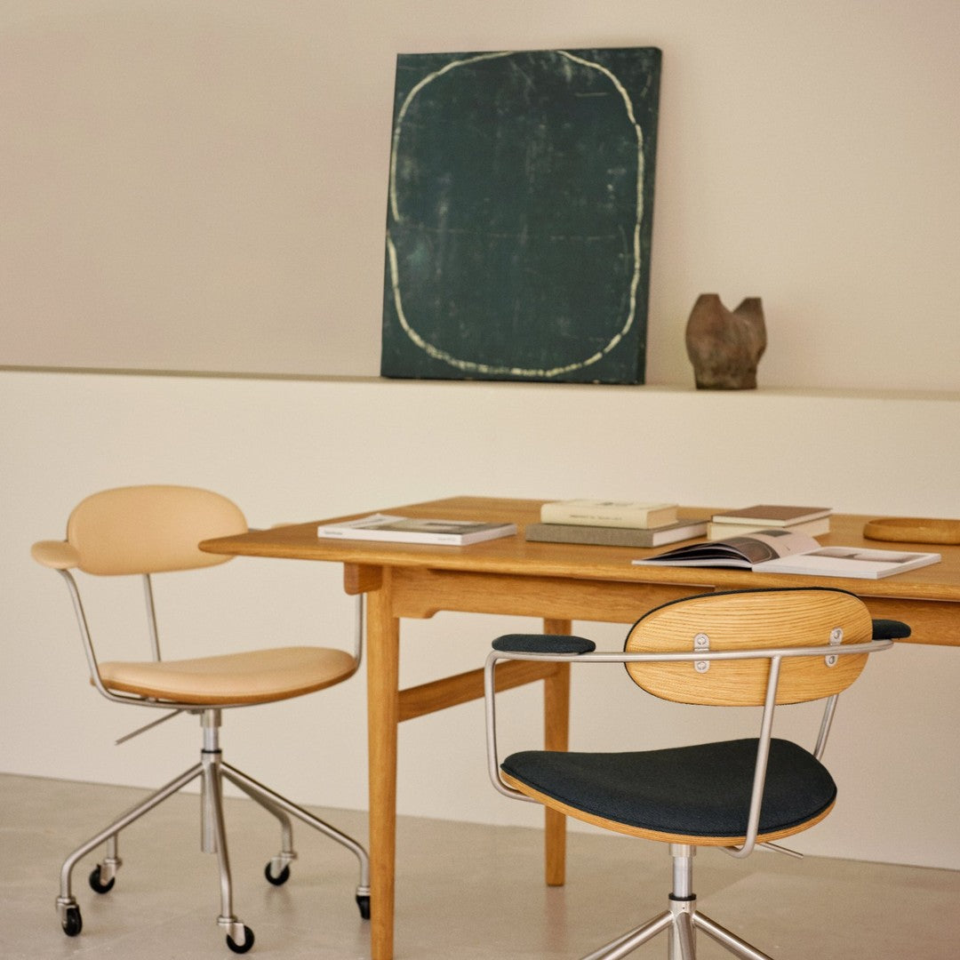 Wooden table with light wooden chairs and dark blue seat cushions, featuring a green abstract painting in the background.
