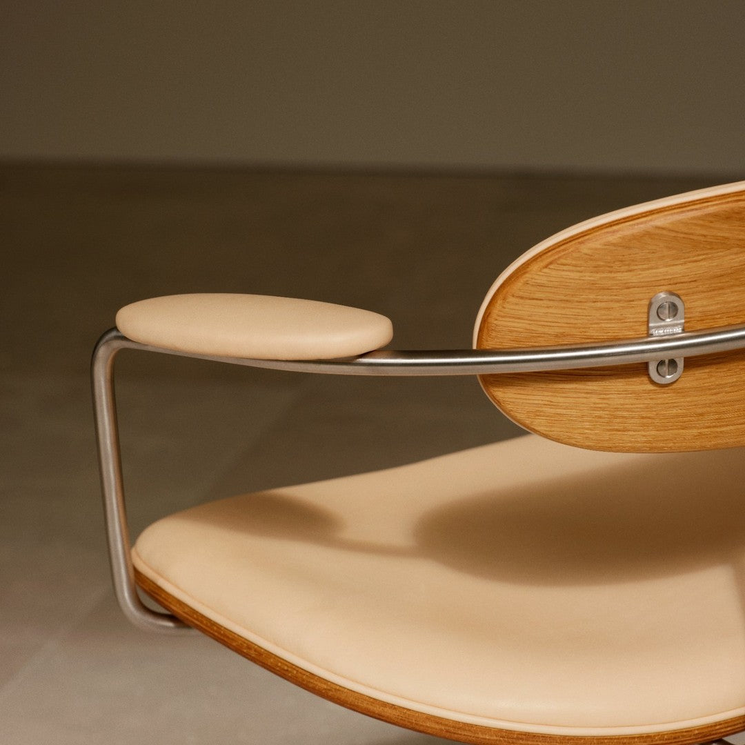 Beige padded seat on a wooden and metal frame, featuring smooth curves and a minimalist design.