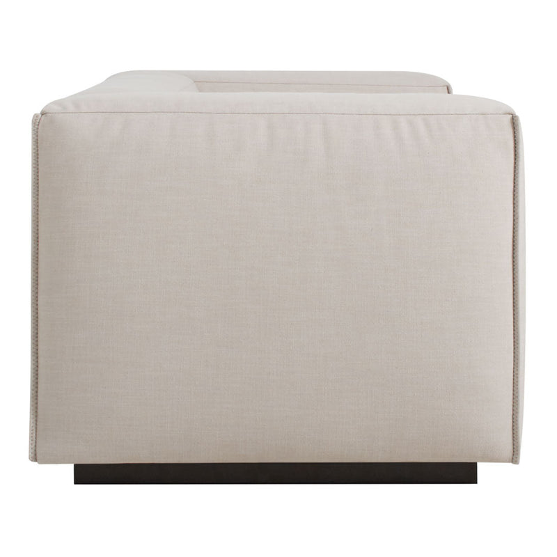 Beige rectangular ottoman with a textured fabric, featuring a sleek dark wood base. Ideal for modern decor.