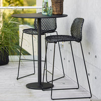 "Stylish black wicker bar stools and table with a modern design, perfect for outdoor settings."