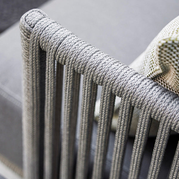 Grey rope detailing on a modern chair frame, paired with a textured green and white cushion.