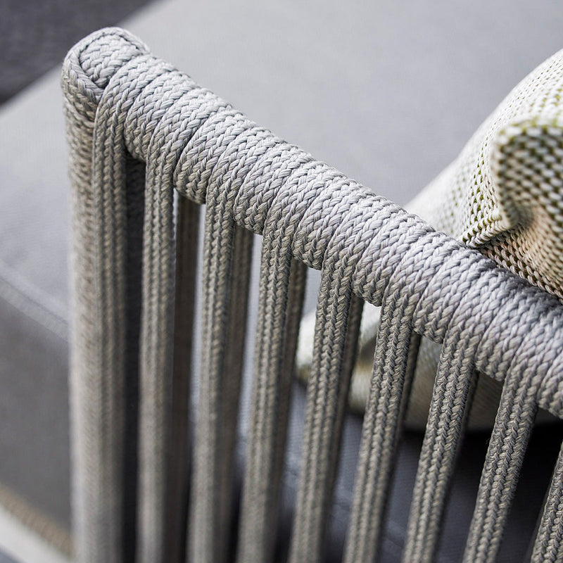 Grey rope detailing on a modern chair frame, paired with a textured green and white cushion.