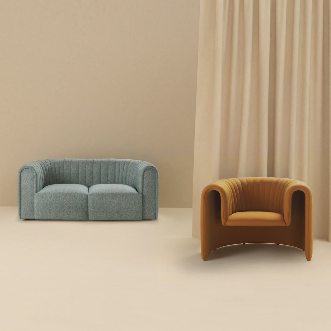 Blue upholstered sofa and caramel armchair with ribbed textures against a soft beige backdrop.