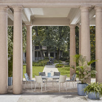 Stylish outdoor dining set featuring gray cushions, white chairs, and a light blue table centerpiece in a serene garden setting.