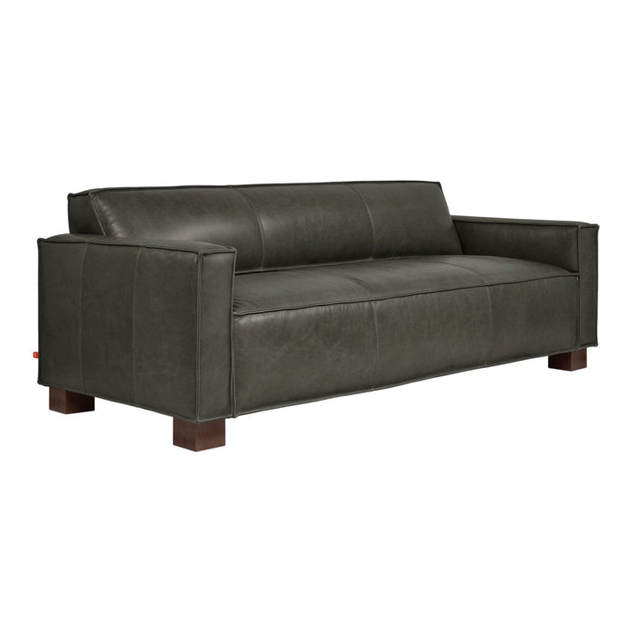 Dark green leather sofa with smooth texture and contrasting wooden legs for a modern aesthetic.