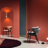 Gray and blush chairs against rich coral and deep blue walls, complemented by a plush burgundy rug. Modern pattern mix.