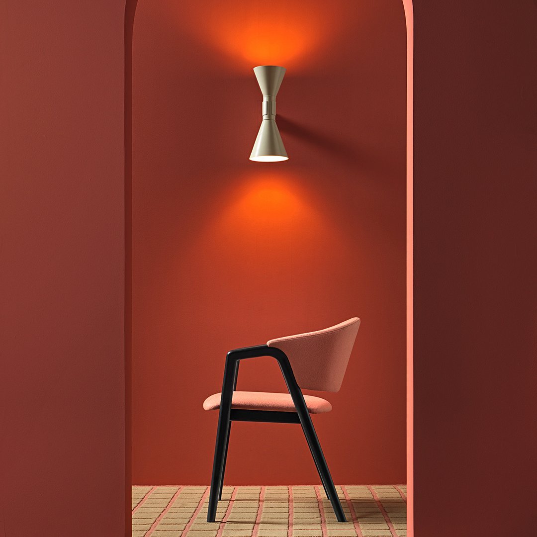 "Stylish pink chair against a warm terracotta wall, complemented by a geometric patterned floor."