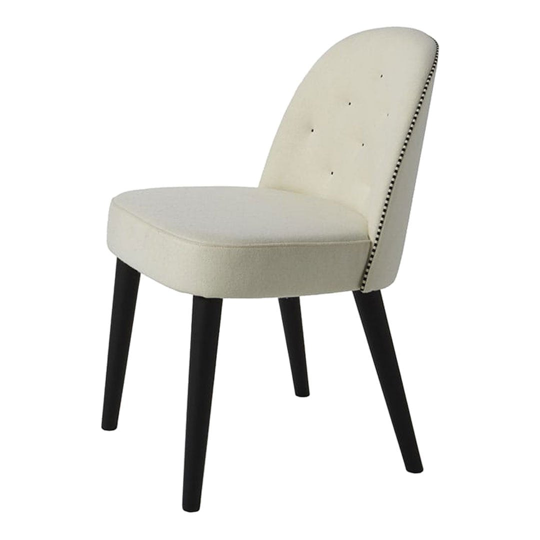 Cream upholstered chair with black wooden legs, featuring a studded pattern along the backrest.