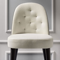 Cream upholstered chair with tufted design and black nailhead trim, featuring dark wooden legs.