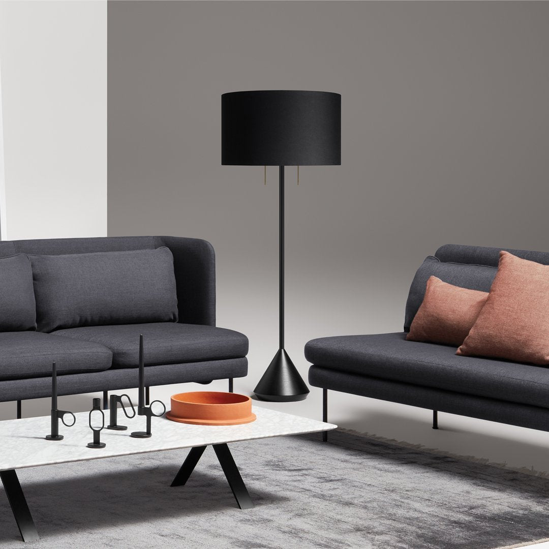 Modern living room with gray sofas, black lamp, and coral accents on cushions and tableware. Subtle neutral background.