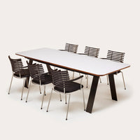 Modern white table with sleek black and silver striped chairs on a neutral background. Perfect for contemporary dining.