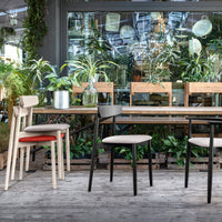 Stylish wooden chairs in beige, black, and red, with minimalist designs, set against a vibrant green backdrop.