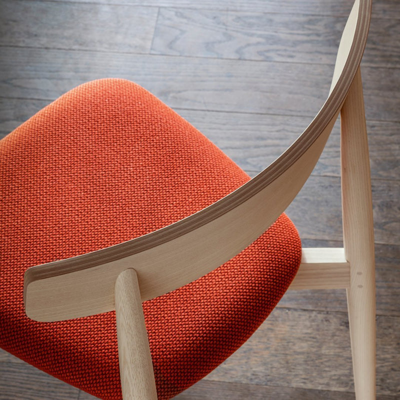 Orange textured cushion with a smooth wood frame, featuring a modern design and warm, inviting colors.
