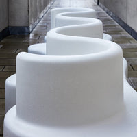 Curvy white foam seating with a smooth, glossy finish, creating a flowing pattern against a gray walkway.