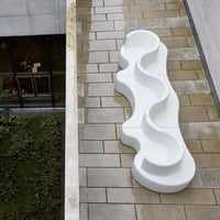 Abstract white wavy outdoor planter with smooth contours on a textured stone surface. Modern design accentuating minimalism.
