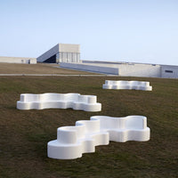 White modern outdoor seating in abstract, cloud-like shapes against a green lawn backdrop.
