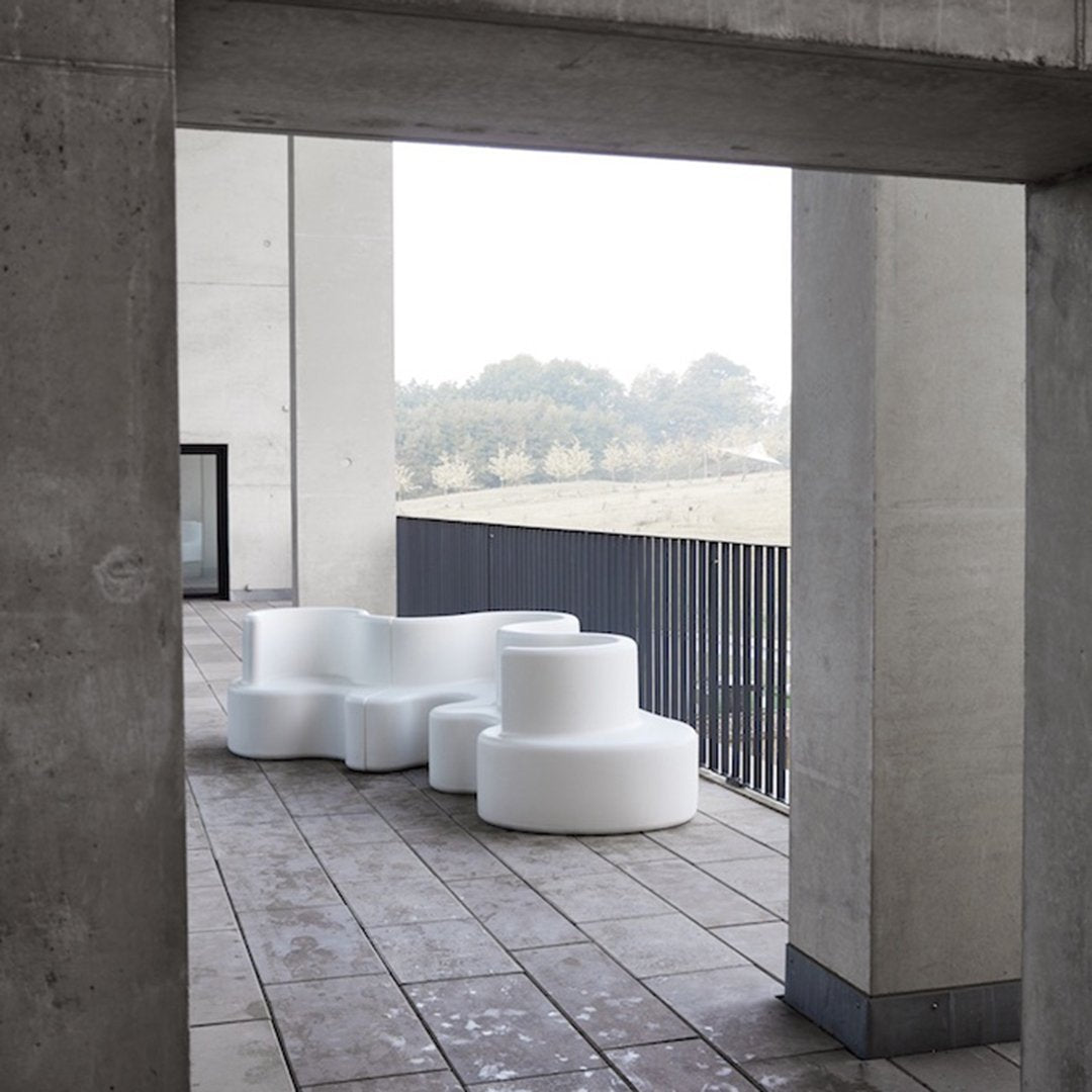 Modern white seating with organic shapes, set against a minimalist concrete background. Ideal for contemporary outdoor spaces.