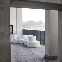 Modern white seating with organic shapes, set against a minimalist concrete background. Ideal for contemporary outdoor spaces.