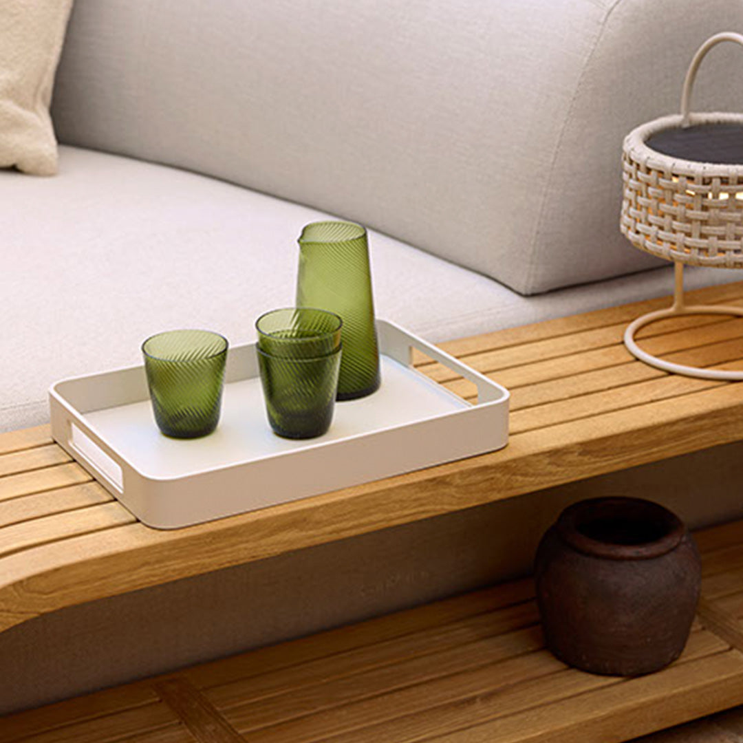 White tray with green glassware on a wooden surface, complemented by natural textures and soft tones.