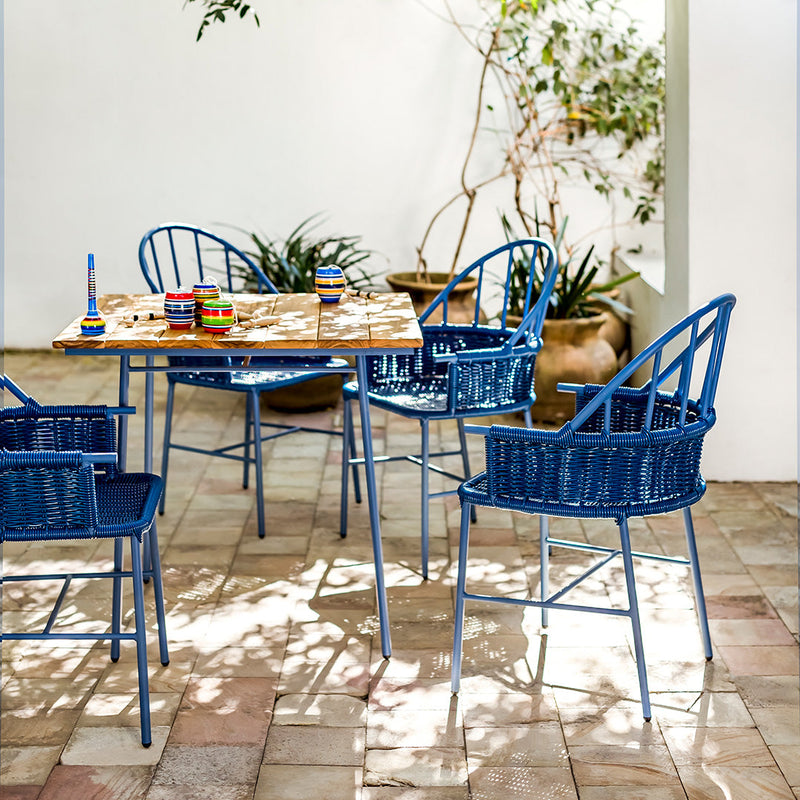 Blue wicker chairs surround a wooden table with a natural finish against a light, serene backdrop.